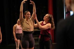 Converse faculty member helps a student adjust a dance position